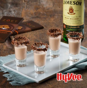 Chocolate milkshake shooters on white plate and rimmed with shaved chocolate