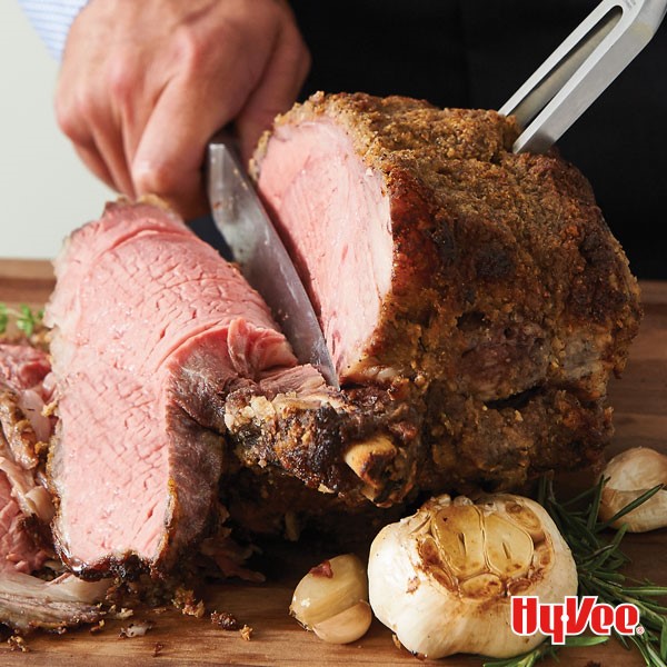 Person cutting slice of crusted prime rib