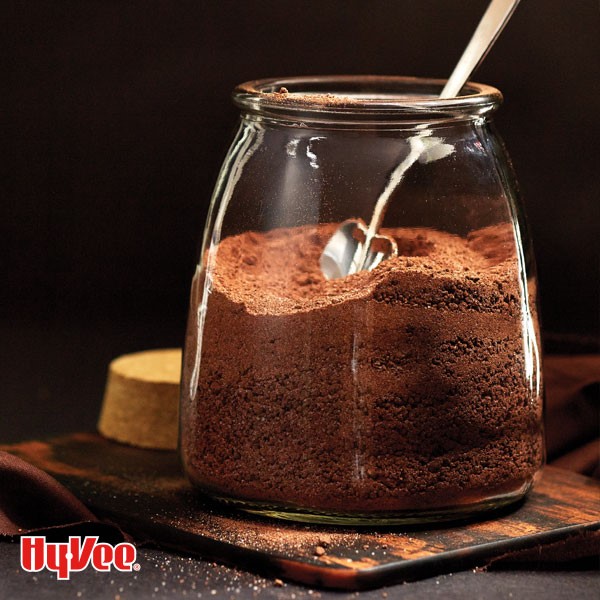Glass jar filled with hot cocoa mix and metal spoon