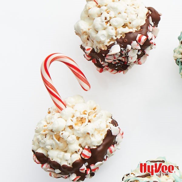 Popcorn balls partially dipped in milk chocolate and attached to candy cane