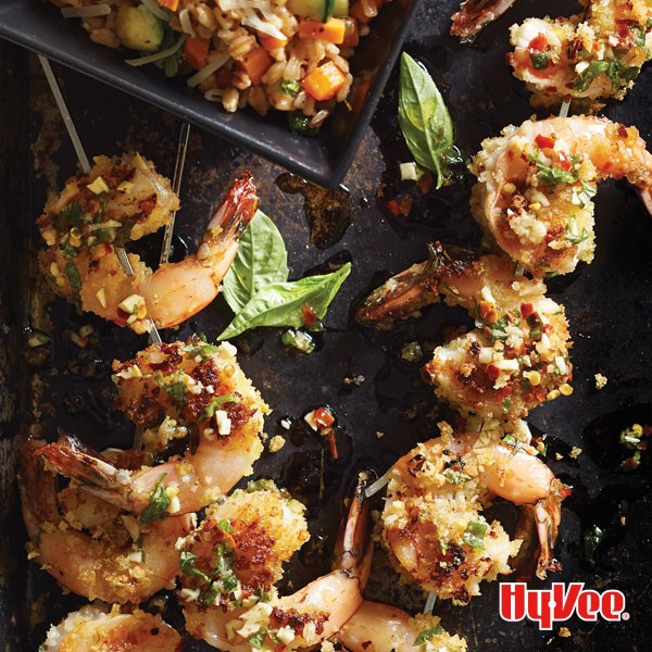 Grilled shrimp skewers garnished with bread crumbs and fresh basil