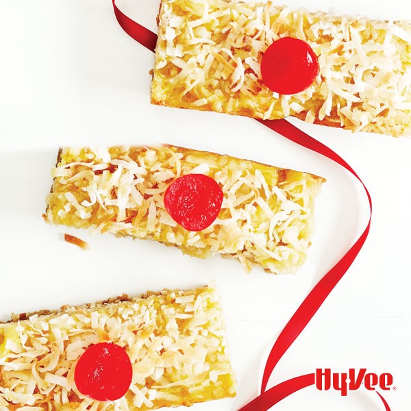 Rectangle bars topped with shredded coconut and a maraschino cherry