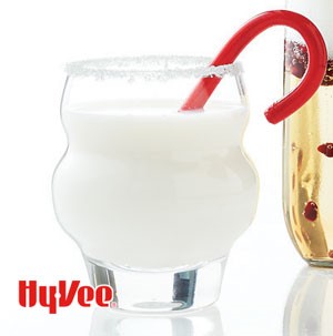 White chocolate beverage in a clear glass with red candycane