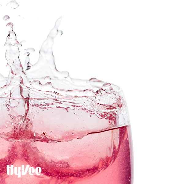 Pink drink splashing out of glass