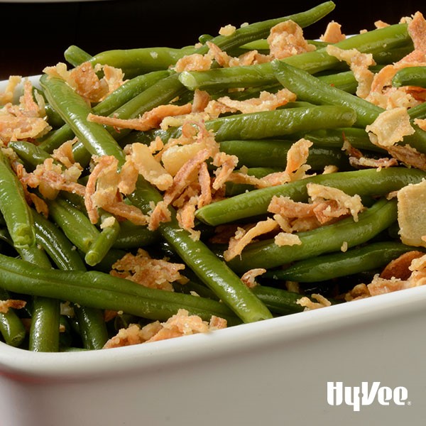 White casserole dish filled with cooked green beans, and crispy onion topping