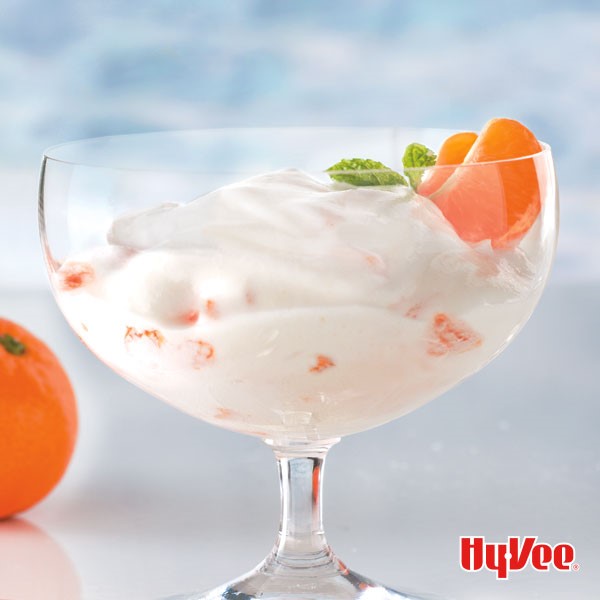 Glass filled with mousse, mandarin slices, and topped with a garnish of fresh mint