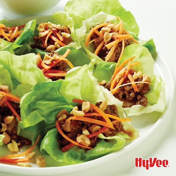 Platter of Asian beef lettuce wraps topped with carrot slices and peanuts