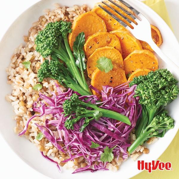 Rice bowl topped with shredded red cabbage, sliced sweet potatoes and broccoli florets 