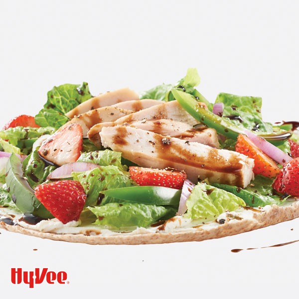 Tortilla topped with fresh greens, strawberry halves, green pepper strips, turkey slices, and balsamic vinegar 