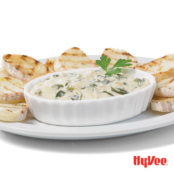 Bowl of spinach and artichoke dip, served with plate of bread