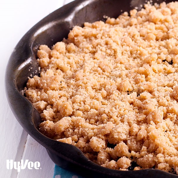 Black scalloped ban filled with cranberry apple pie and garnished with a crumb topping