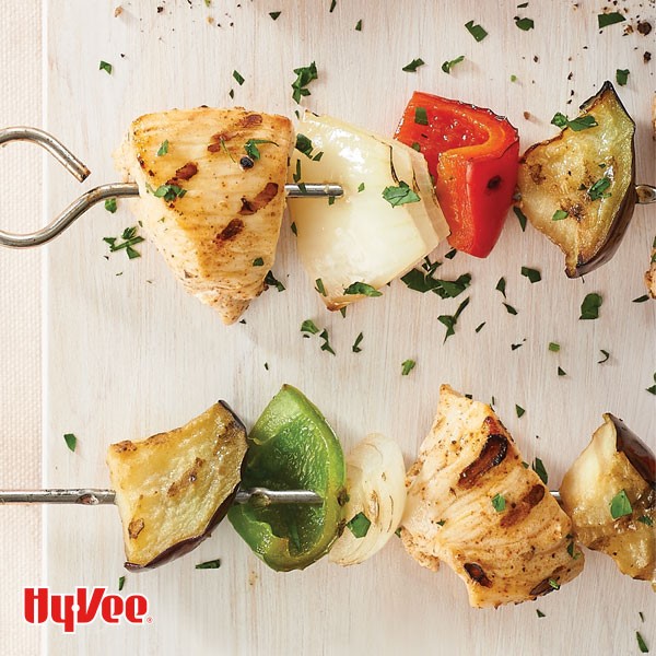 Metal skewers with pieces of grilled chicken, white  onion, red bell pepper, and eggplant 