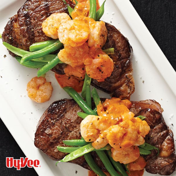 Grilled steaks topped with green beans and tomato cream covered shrimp