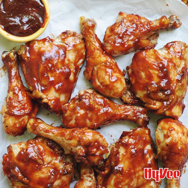 Classic barbecue chicken served with side of barbecue sauce on parchment paper