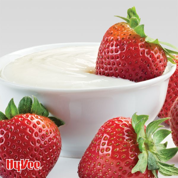White fruit dip in a serving bowl with whole strawberries on the side