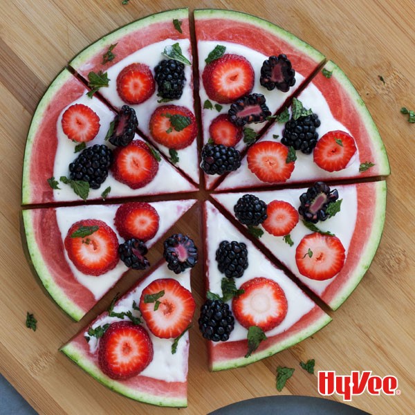 Sliced watermelon topped with sliced strawberries, black berries, and chopped mint