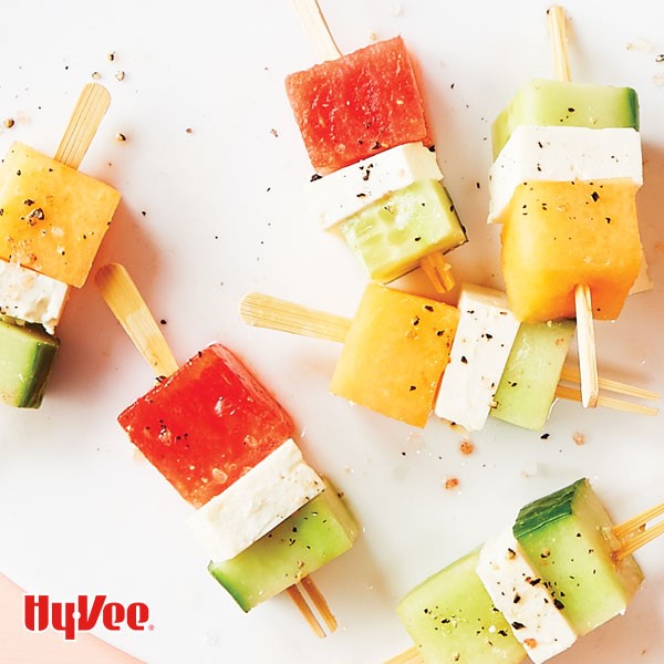 Square cut cucumbers, cheese, and melon on wooden sticks and sprinkled with salt and ground black pepper