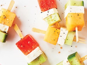 Square cut cucumbers, cheese, and melon on wooden sticks and sprinkled with salt and ground black pepper