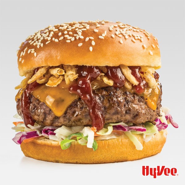 Cheeseburger with slaw, barbecue sauce and fried onions sandwiched between a sesame seed bun