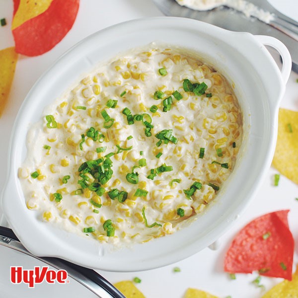 Corn dip garnished with chives in a slow cooker