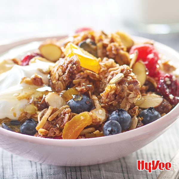 Bowl of almond granola topped with yogurt, honey and fresh fruit