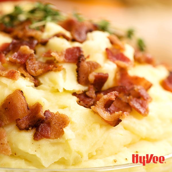 Mashed potatoes topped with cooked chopped bacon with fresh thyme sprigs