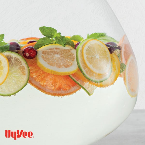 Spritzer filled bowl with sliced citrus, mint leaves and whole cranberries