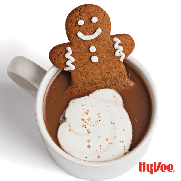 White mug filled with gingerbread latte, whipped topping, and a decorated gingerbread man