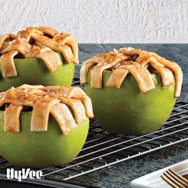 Green apples topped with a lattice pie crust on a cooling rack