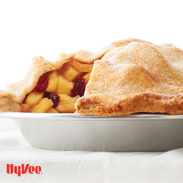 Pie plate filled with cranberry and apple filling and topped with flaky-sugar crusted pie crust