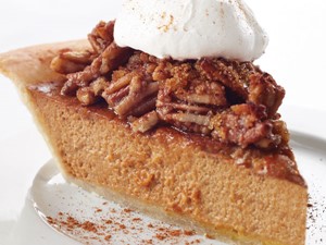 Pumpkin pie topped with pecans, whipped cream, and ground cinnamon