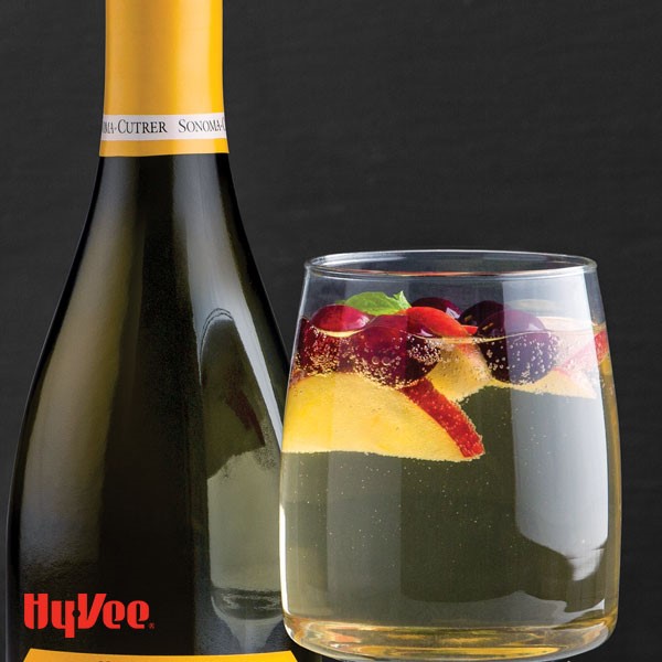 Glass of sparkling apple chardonnay, garnished with apple slices, berries and mint