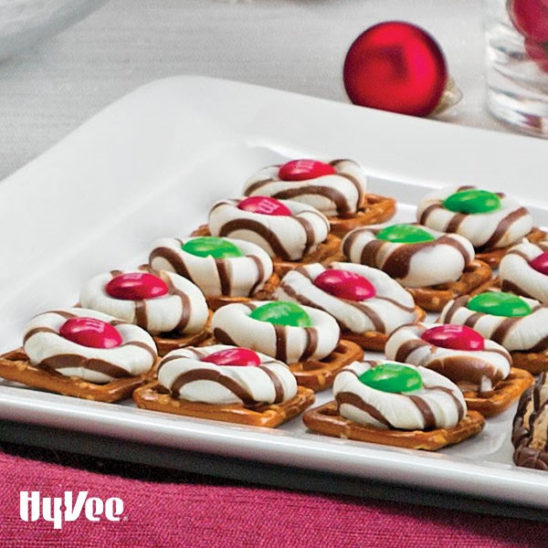 Pretzels topped with white and milk striped candies with green and red candy-coated chocolates on top