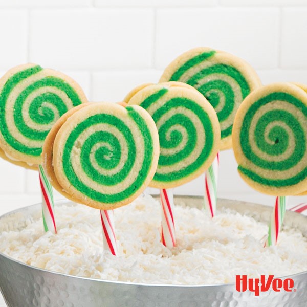 Green-swirled cookie pops held with candy cane in a bucket of rice