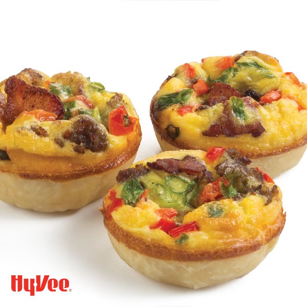 Small quiches topped with bacon slices, cheese, peppers, and sliced green onion