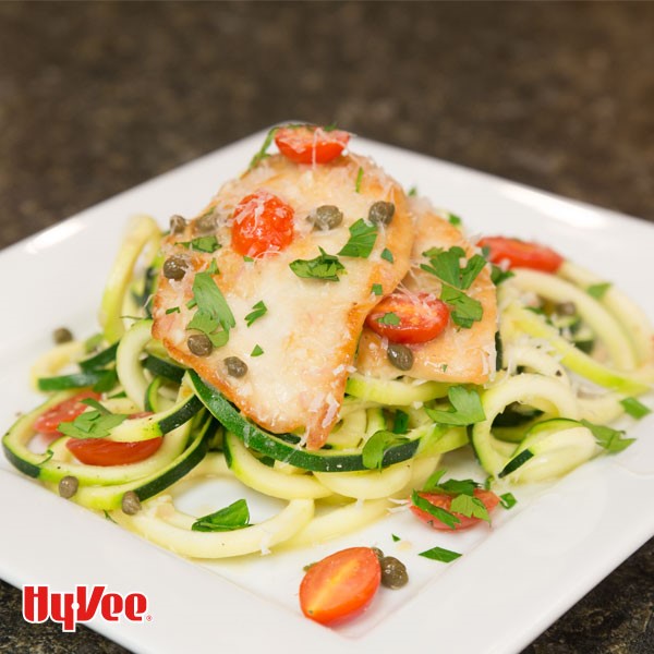 Plate of chicken piccata over zucchini noodles and cherry tomatoes