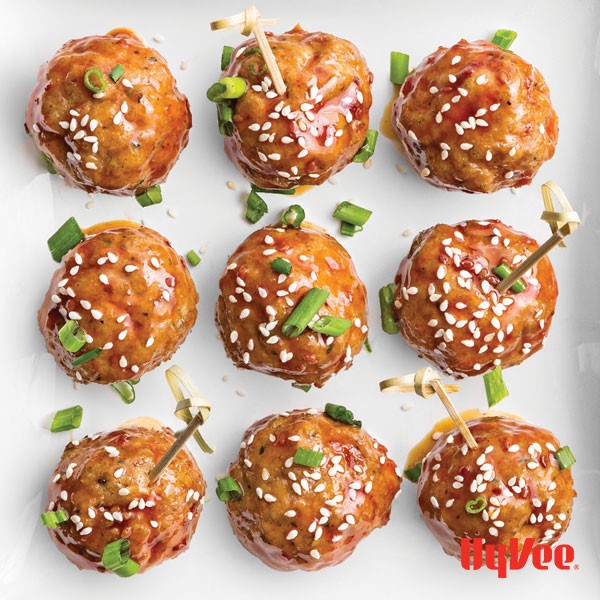 Plate of turkey meatballs coated in teriyaki sauce and garnished with sesame seeds and scallions