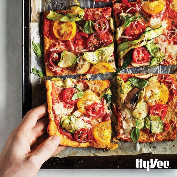 Tray of cauliflower crust pizza topped with cheese and vegetables
