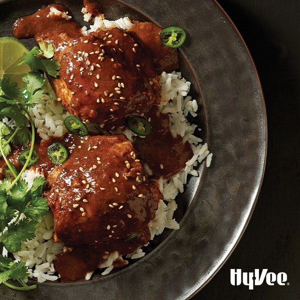 Platter of chicken thighs coated in mole sauce and served with rice