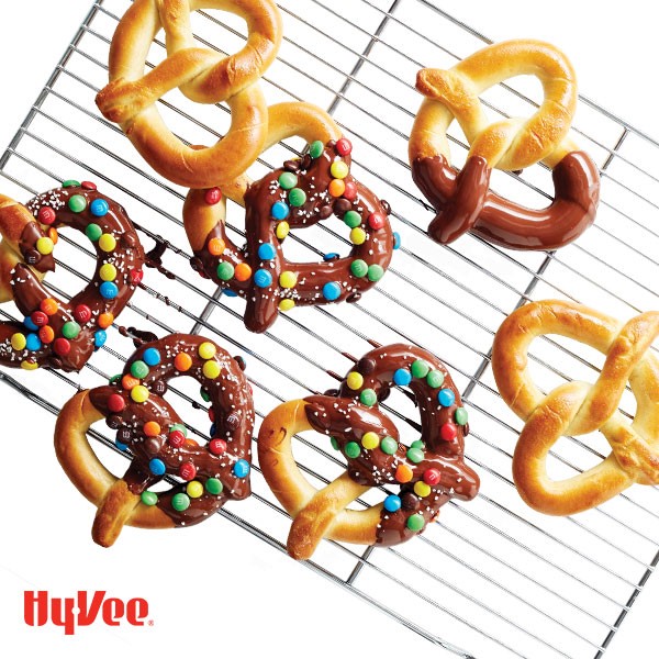 Soft pretzels dipped in melted chocolate and M&M's on a wire rack