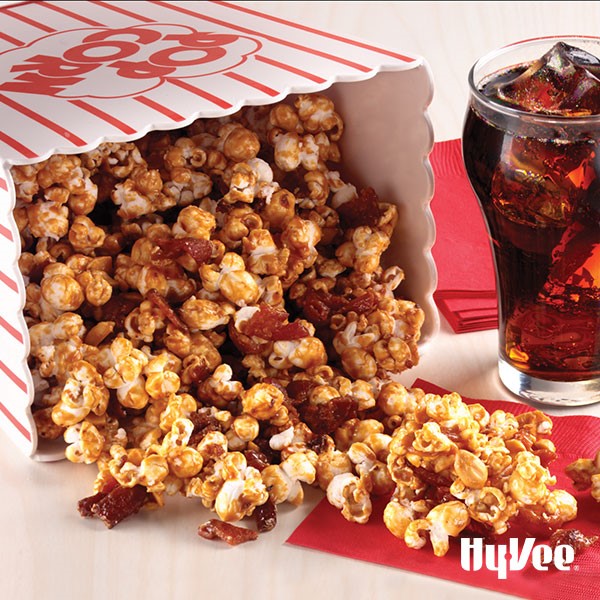 Popcorn bag toppled over with bacon and caramel corn spilling out