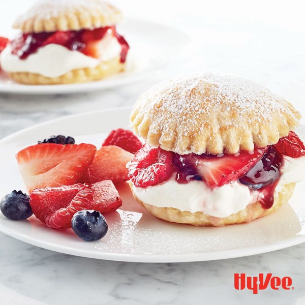 Cream puff pastries filled with whipped cream, and mixed berries garnished with powdered sugar