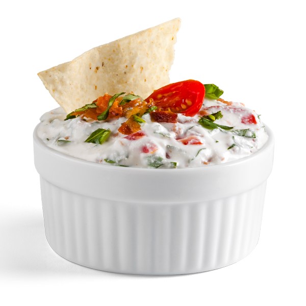 Ramekin filled with bacon, basil, and tomato dip with flour tortilla chip for garnish