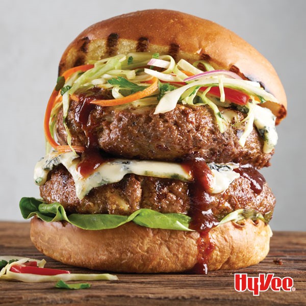 Bun topped with lettuce, two hamburger patties, blue cheese and shredded tricolor coleslaw