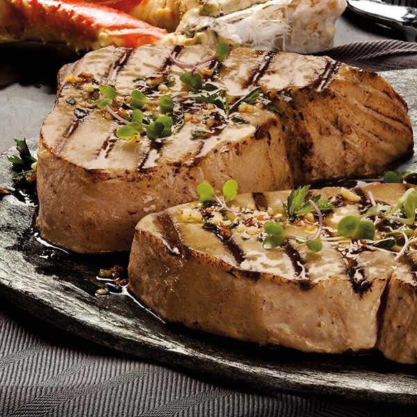 Grilled tuna steaks with garlic olive oil and garnished with fresh oregano and parsley