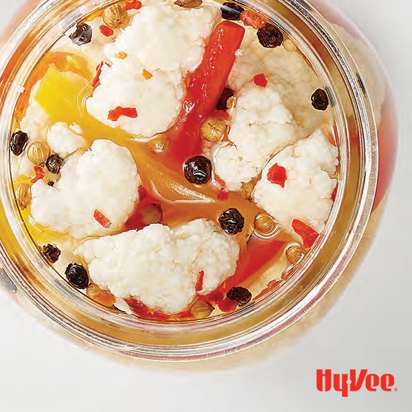 Cauliflower, sliced red and yellow bell peppers and whole spices in mason jar