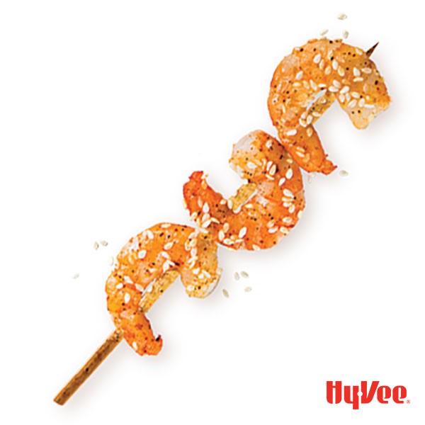 Three shrimp on wooden skewer sprinkled with black pepper and sesame seeds