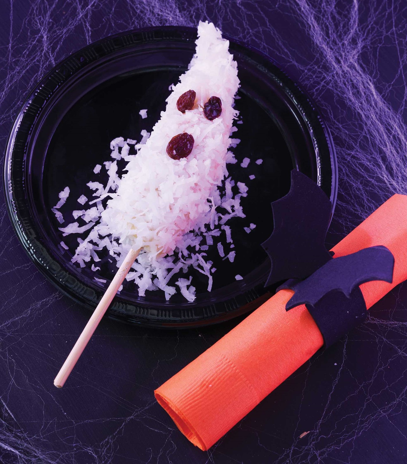 Half of a Banana covered in Shredded Coconut and Topped with Two Raisin Eyes and Mouth