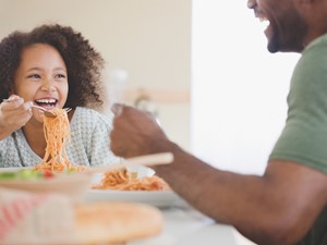 Girl Eating Pasta with Dad in the Kitchen