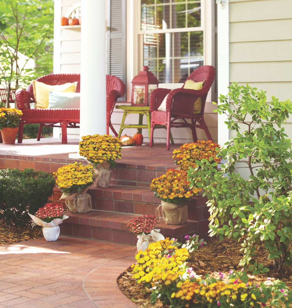Porch lined with red, orange, and yellow mums